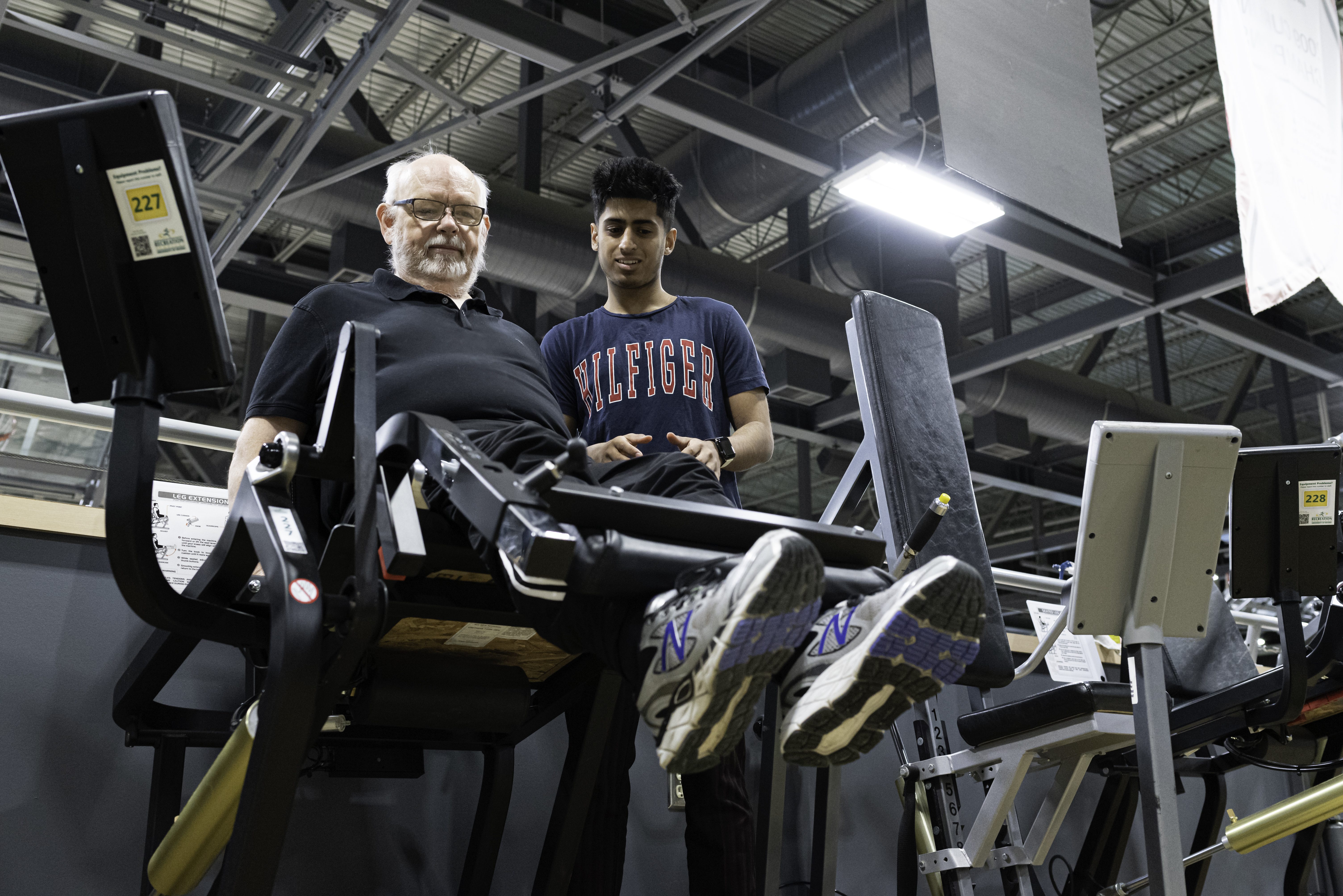 Ali Khan works with Allan Johnson as he does leg presses in the gym at the University of Regina. (Photo by Michael Bell)