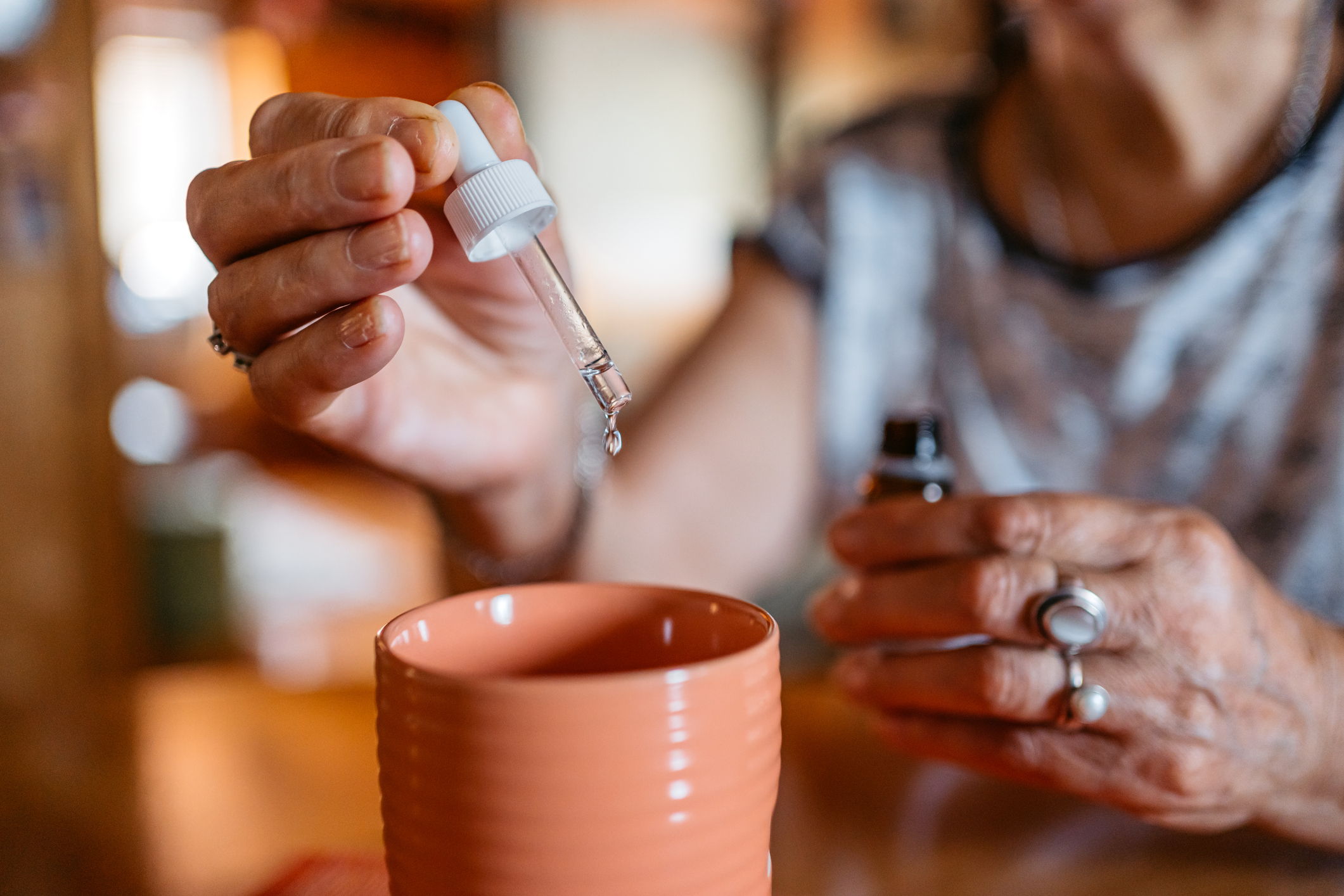 Senior Woman Putting Medicine Drops In A Glass Of Water