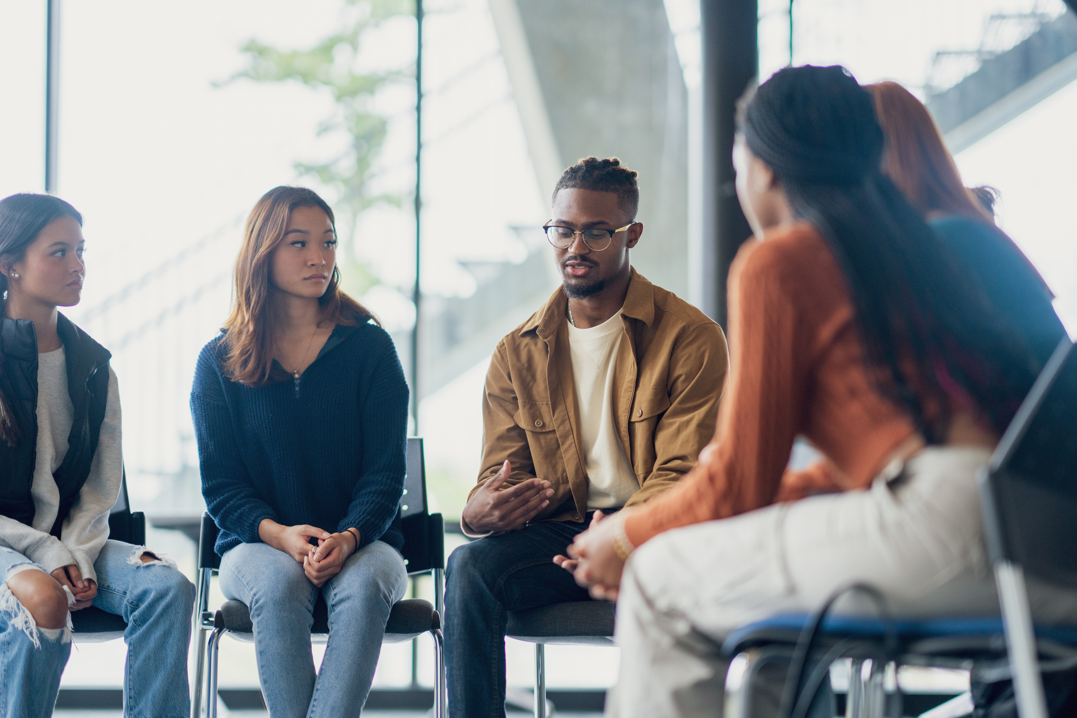 Student Counselling A small group of University students sit together during a group therapy session. They are each dressed casually as they take turns sharing their struggles with the group.